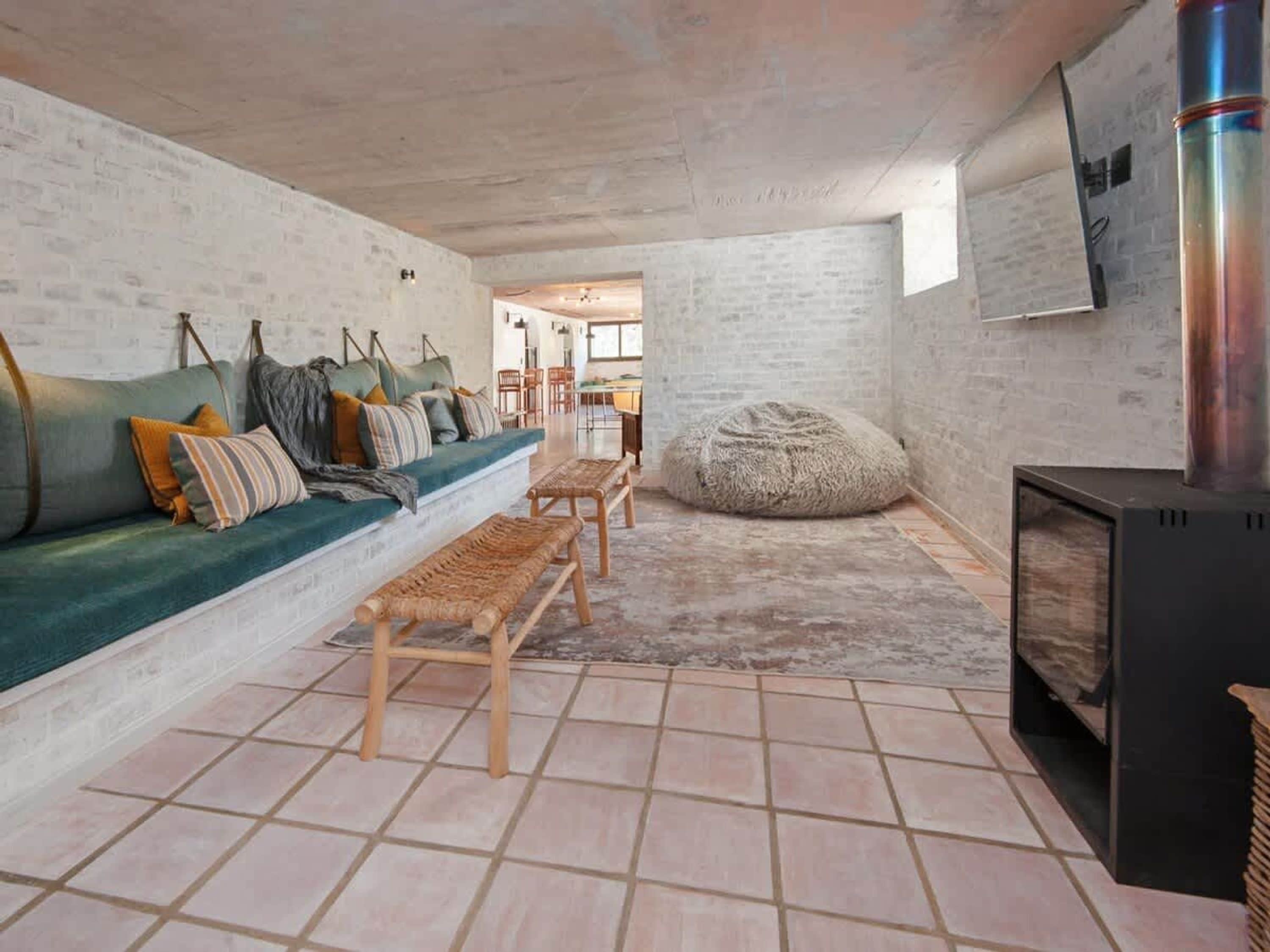 A cozy living room with a sofa, bench seating, a bean bag, and a fireplace.