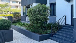 Um edifício residencial com várias andares, varandas, escadaria e área de jardim.