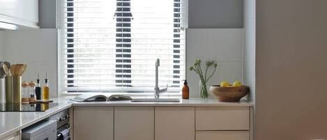 A modern kitchen with a window, a sink, and a dining area with chairs.