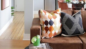 Uma sala de estar moderna com um sofá marrom, uma mesa de centro e uma área de jantar com mesa e cadeiras.