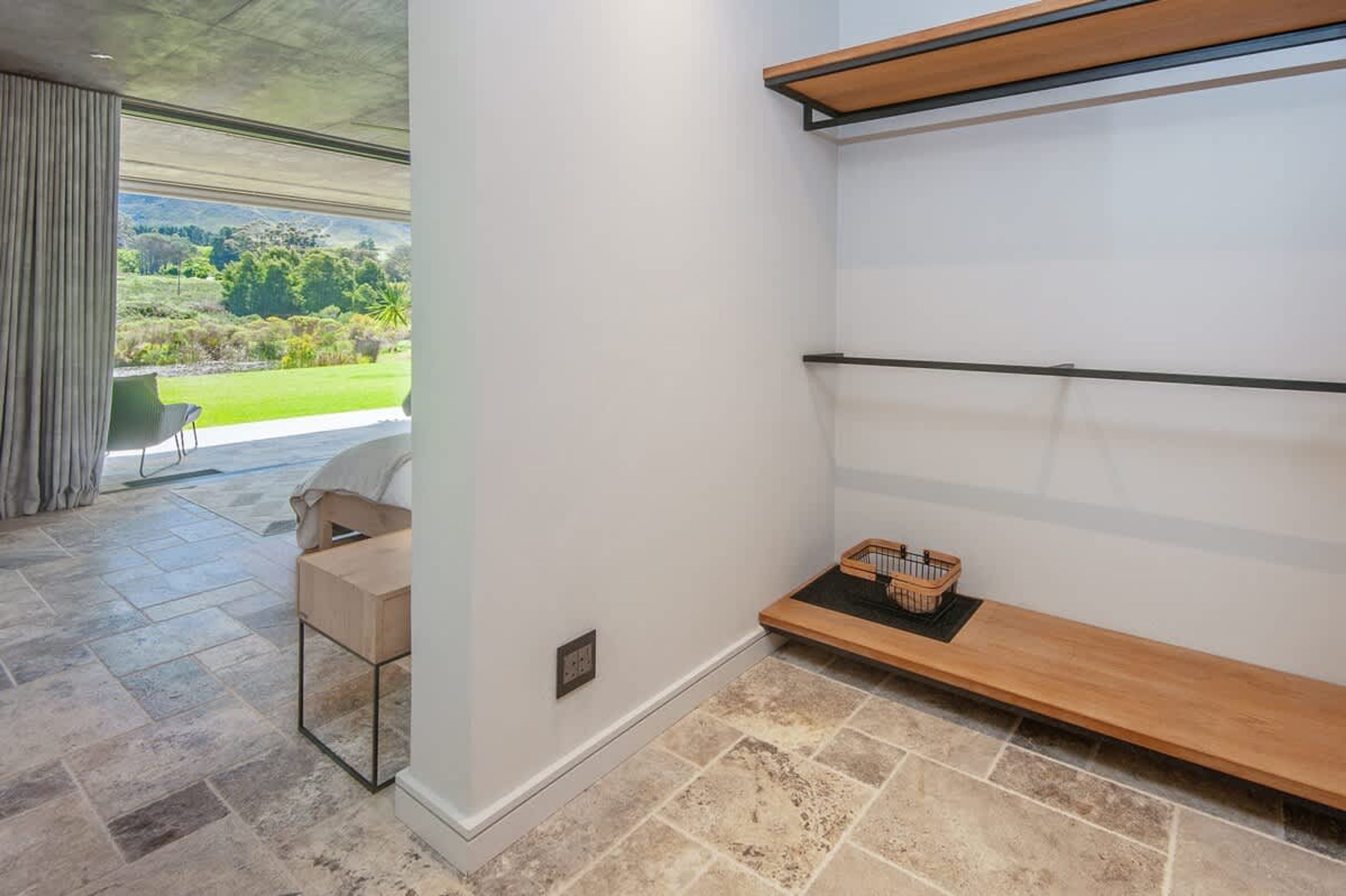 Una habitación moderna con vistas a un paisaje verde, un banco de madera y una silla.