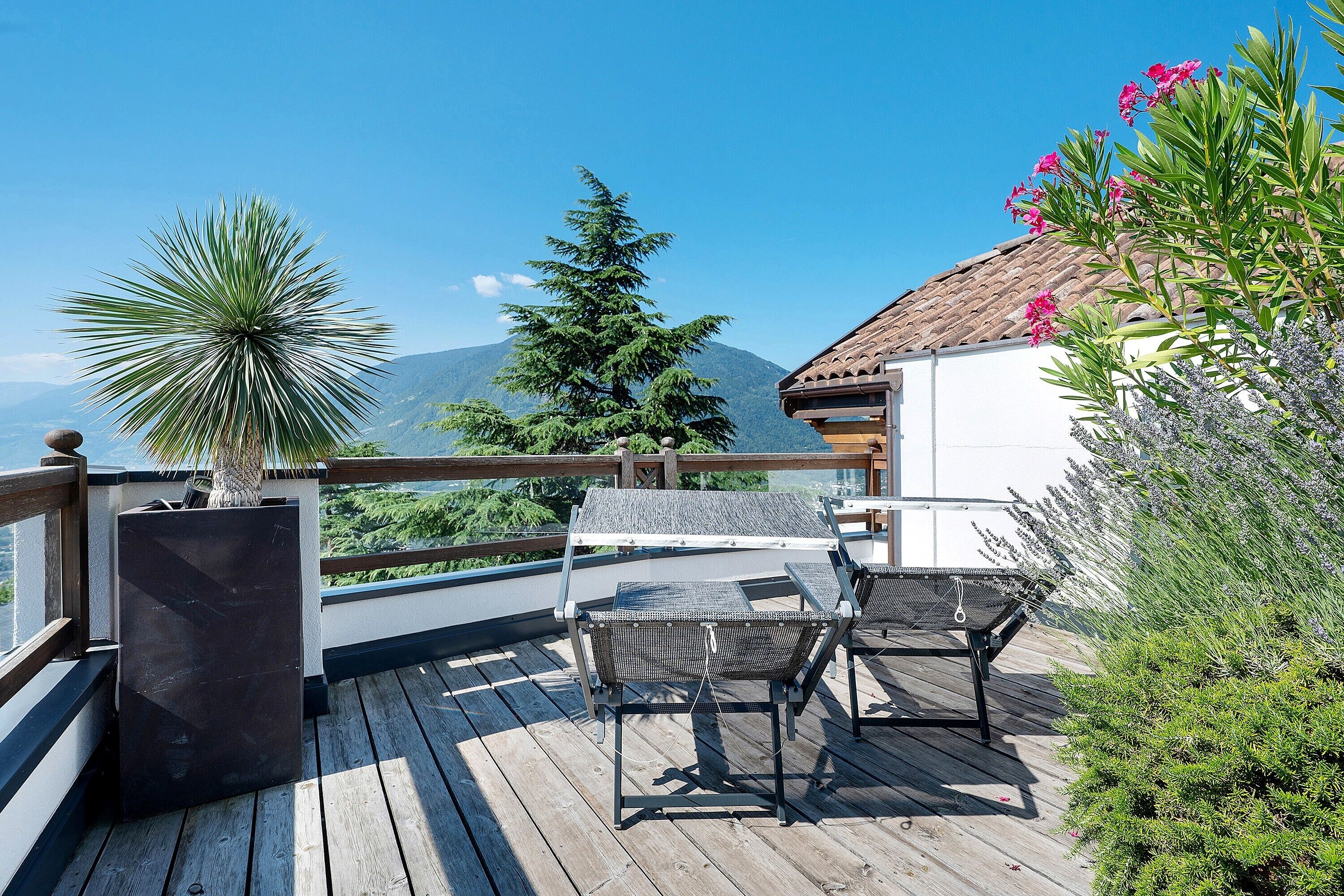 A wooden deck with outdoor seating and a view of mountains.