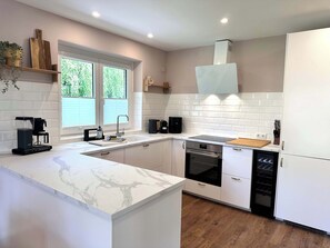 Une cuisine moderne avec des meubles blancs, un plan de travail en marbre, un four encastré et un lave-vaisselle.
