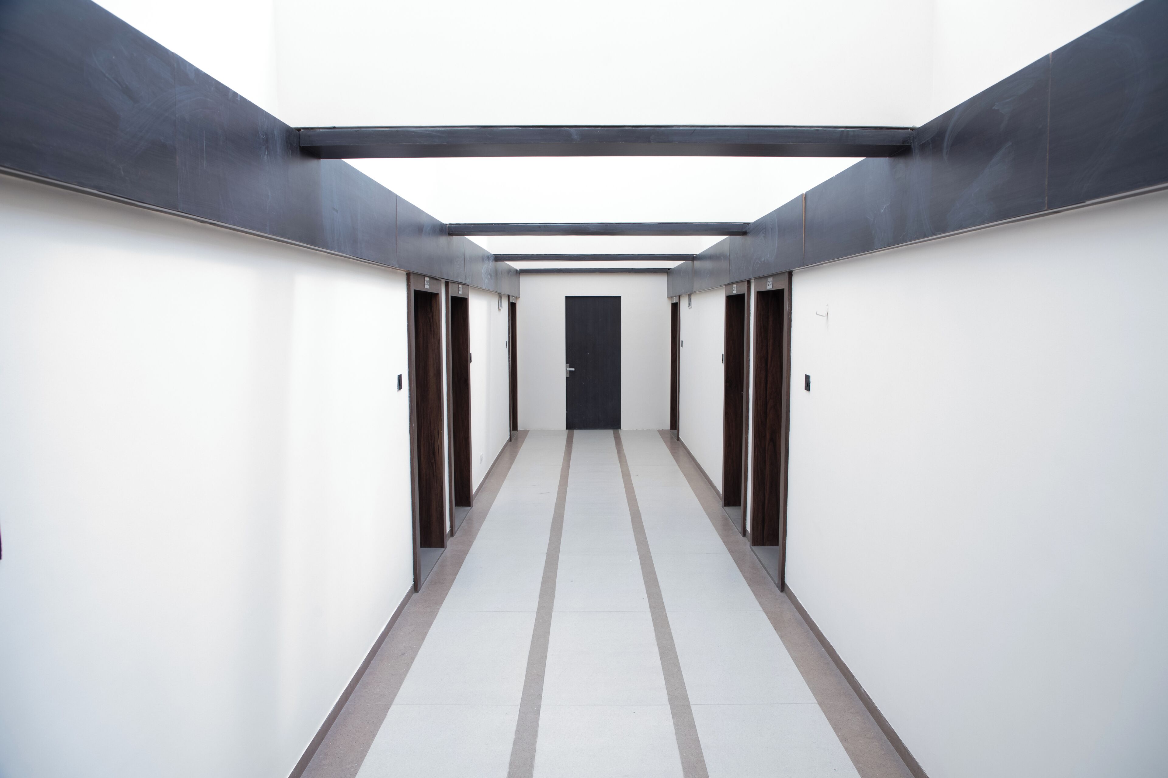 Un passadís amb portes a ambdós costats, que condueix a una porta central al final.