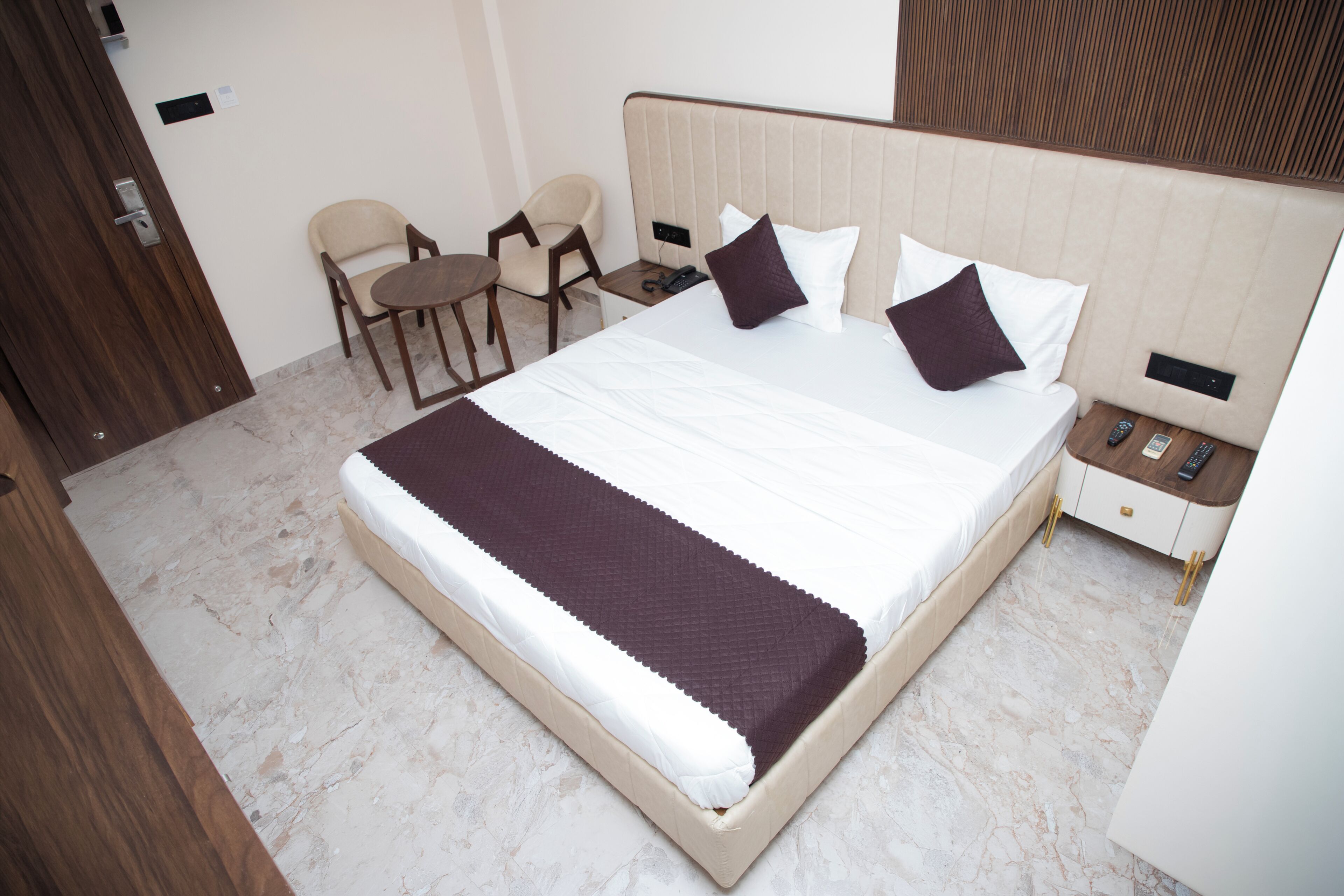 A hotel room with a large bed, bedside tables, a chair, and a desk.