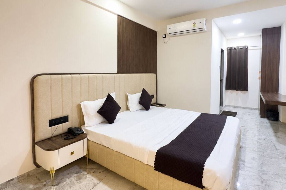 A modern hotel room with a bed, bedside table, nightstand, and a ceiling fan.