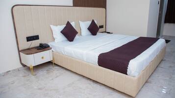 Una cama bien hecha con cabecera, una mesita de noche con un teléfono y un mueble con cajones.