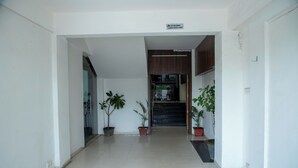 A hallway with potted plants, a sign indicating surveillance, and a staircase leading to an upper floor. - Hotel White Desert (Bhuj)