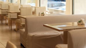 Cafetería con un interior moderno y luminoso, que presenta sofás color beige y mesas de madera.