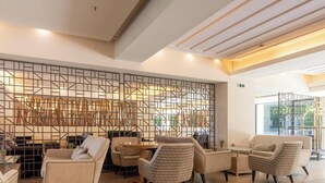 Un interior moderno con zona de estar, una pared decorativa y vistas a través de un ventanal.