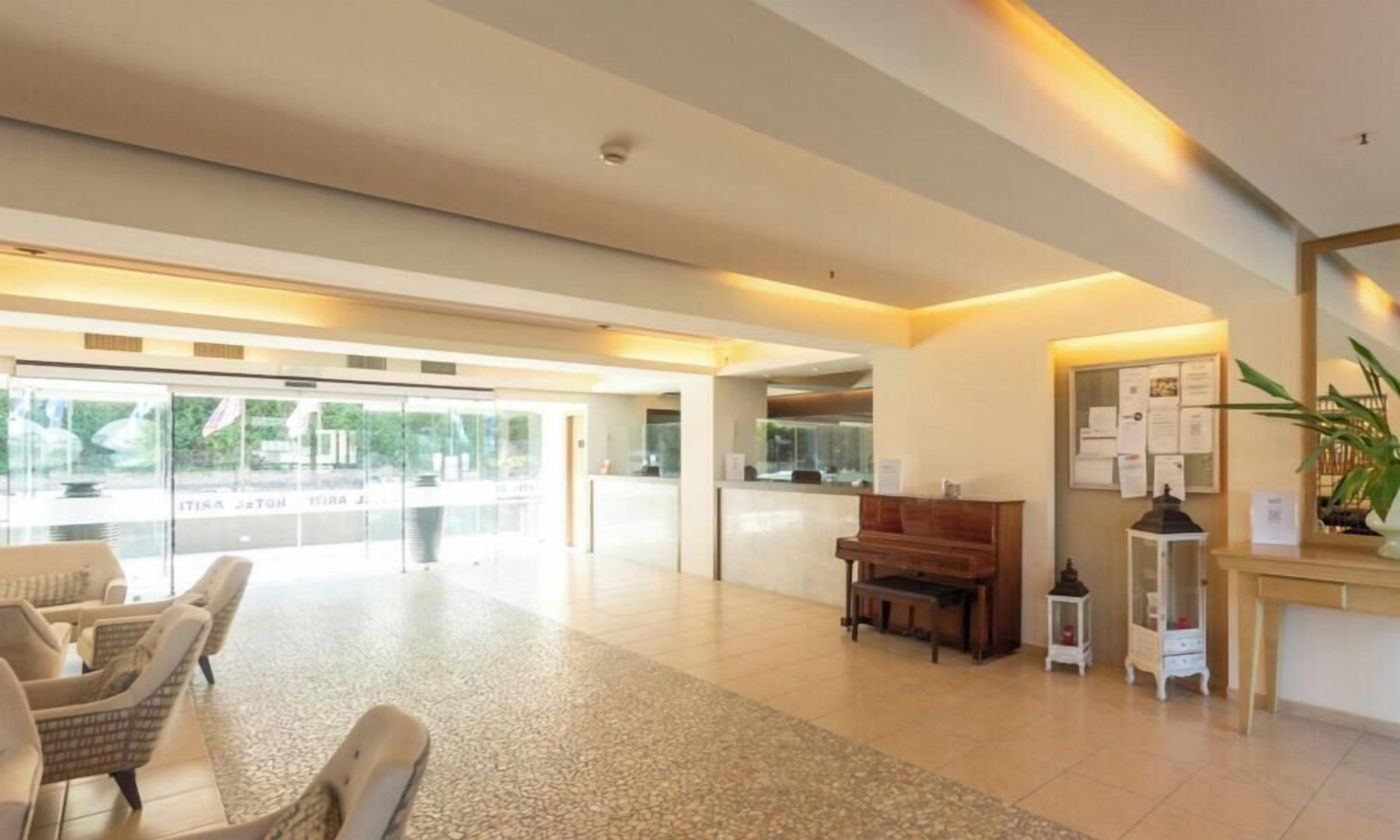 A spacious lobby with a piano, seating area, and a reception desk.