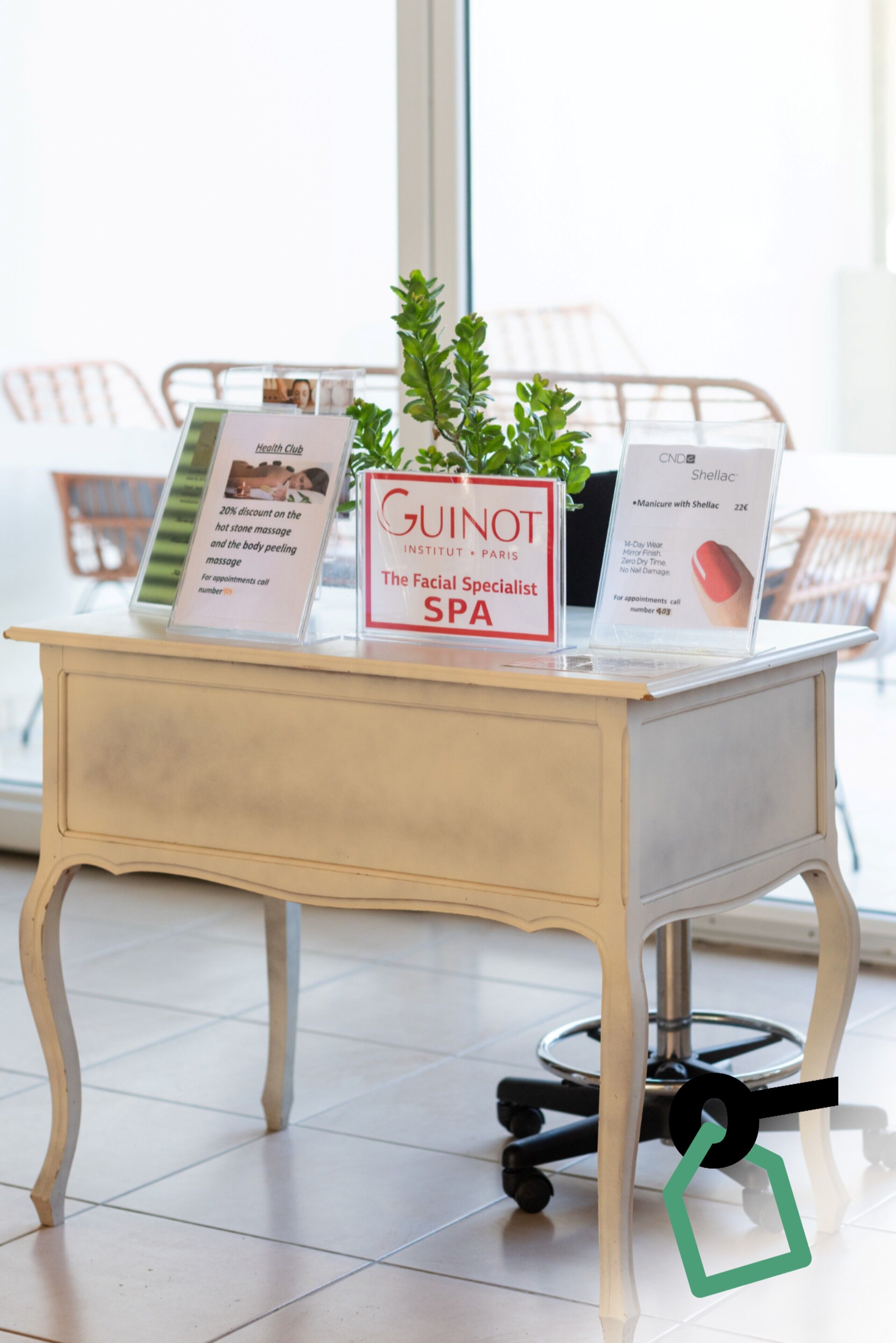 A desk with promotional materials for a facial spa, a potted plant, and a chair in the background.