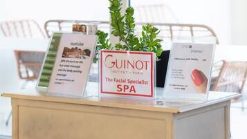 A desk with promotional materials for a facial spa, a potted plant, and a chair in the background.