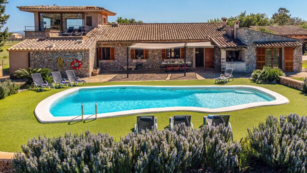 Ein Haus mit Swimmingpool, Sitzgelegenheiten im Freien und einer Steinfassade.