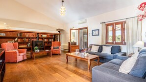 Ein Wohnzimmer mit Kamin, einer Couch, einem Sessel und einem Bücherregal.