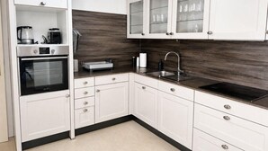 A modern kitchen with white cabinetry, a built-in oven, a sink, and a coffee maker.