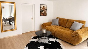 A living room with a sofa, a round coffee table, a mirror, and a framed picture on the wall.