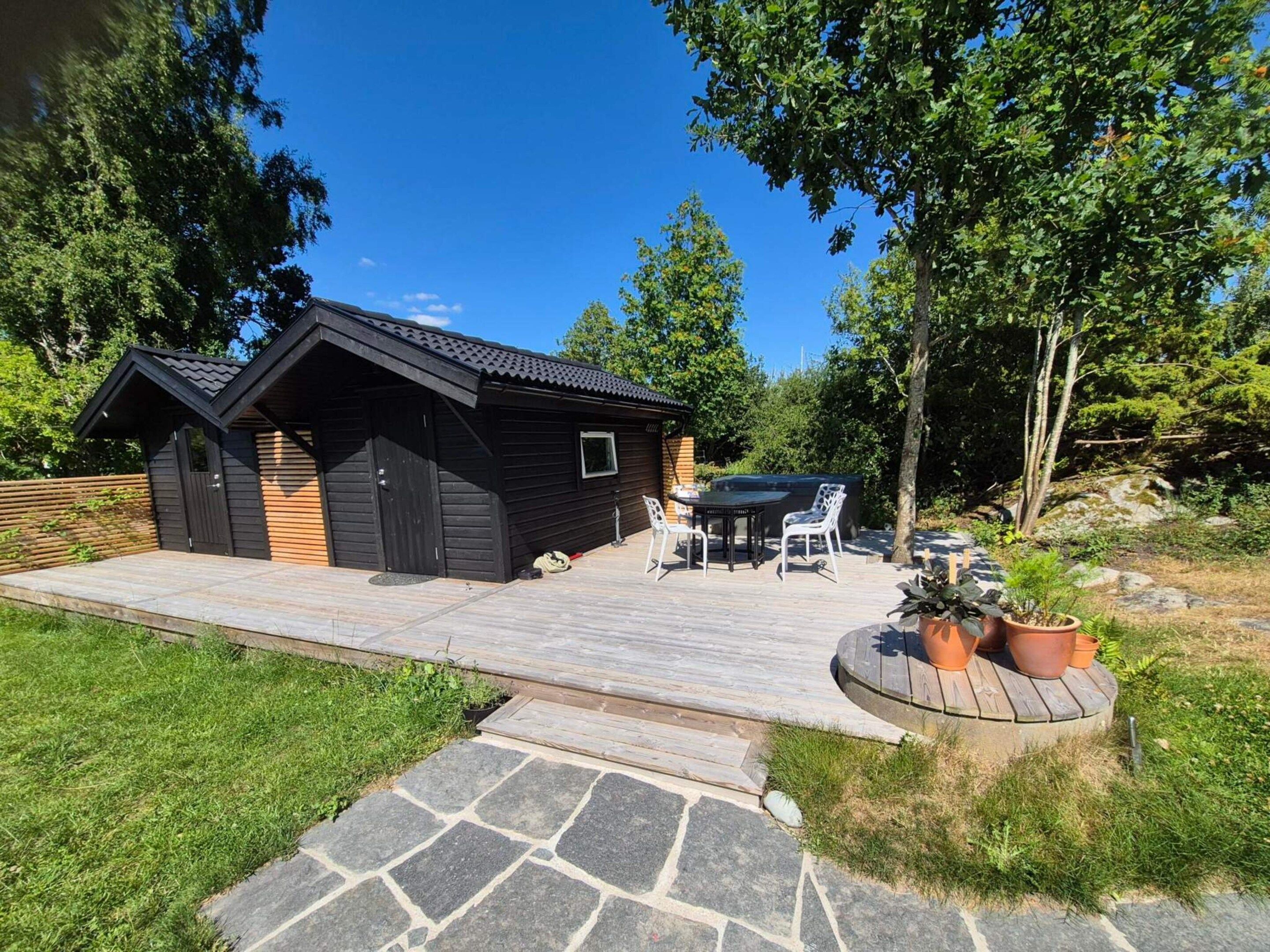 Un piccolo chalet in legno con un patio, un tavolo e sedie.