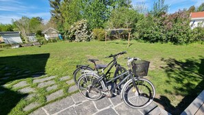 Un chemin de pierres mène à une terrasse en bois où sont garés deux vélos.