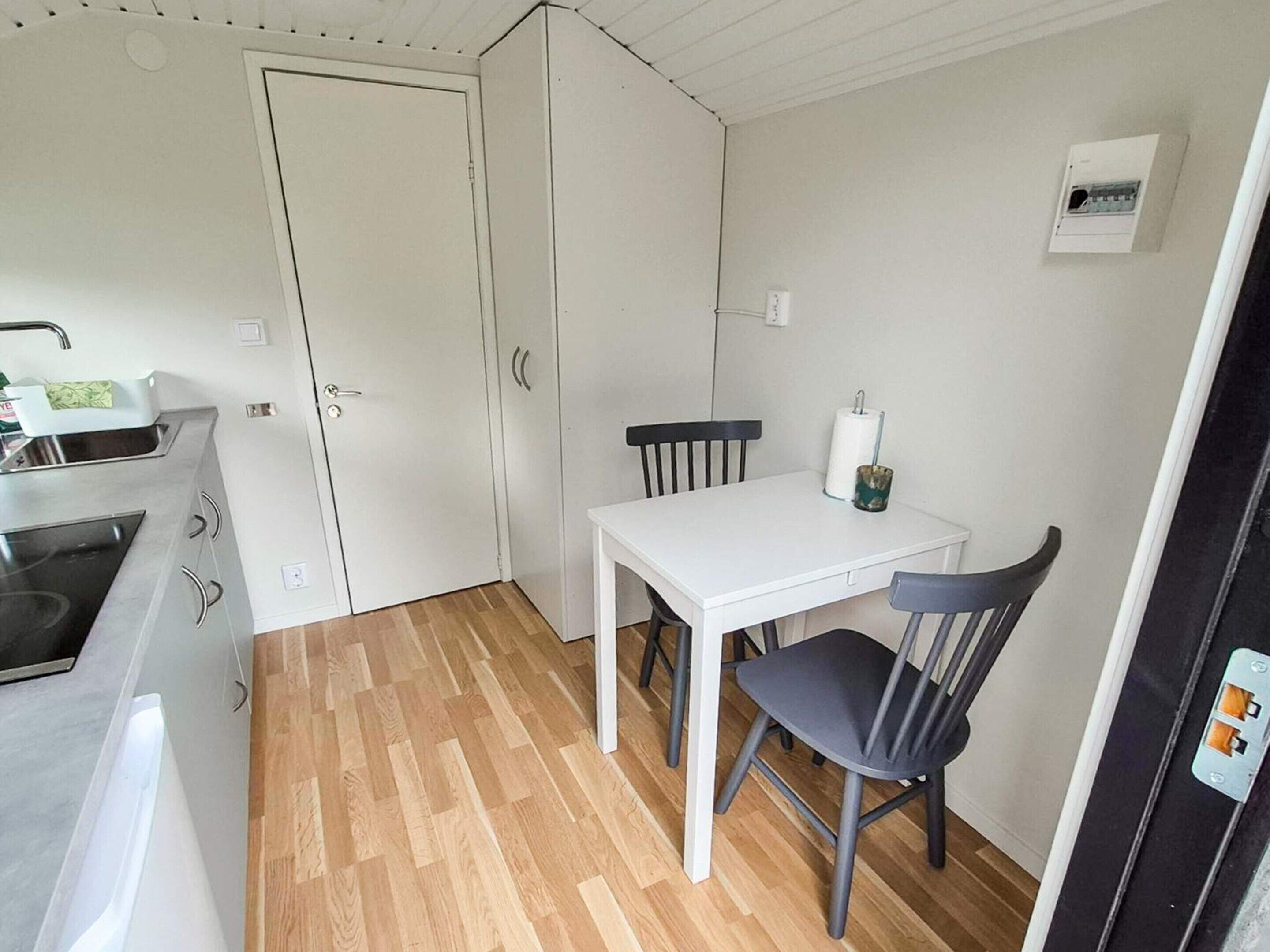 A compact kitchen with a stove, a white table, and two chairs.