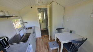 Une cuisine de taille réduite, équipée d’un évier, d’une cuisinière et d’une petite table à manger avec des chaises.