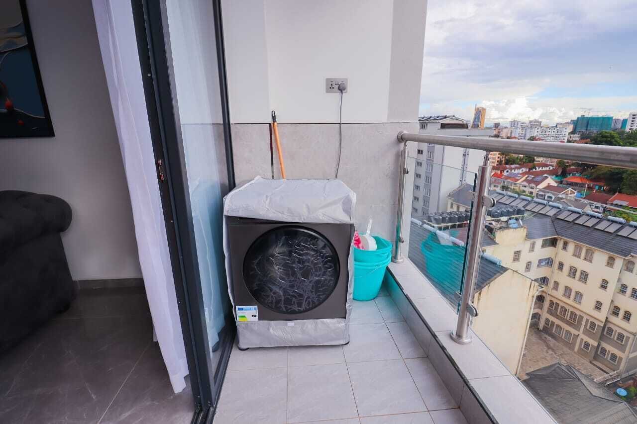 Ein Balkon mit Waschmaschine, Besen und Eimer.