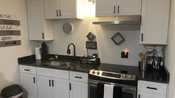 A modern kitchen with white cabinets, a stainless steel sink, and a built-in oven.