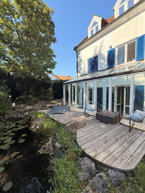 A house with a deck, a pond, and a garden.