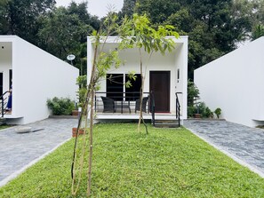 A modern building with a flat roof, a small patio with outdoor furniture, and a well-maintained lawn.