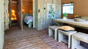 A wooden interior with a bed, bench seating, a painting, and a window.