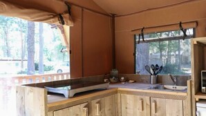 A kitchen with a large island, wooden cabinets, a sink, and a window overlooking a wooded area.
