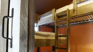 A bunk bed room with a wooden ladder and a metal handle.