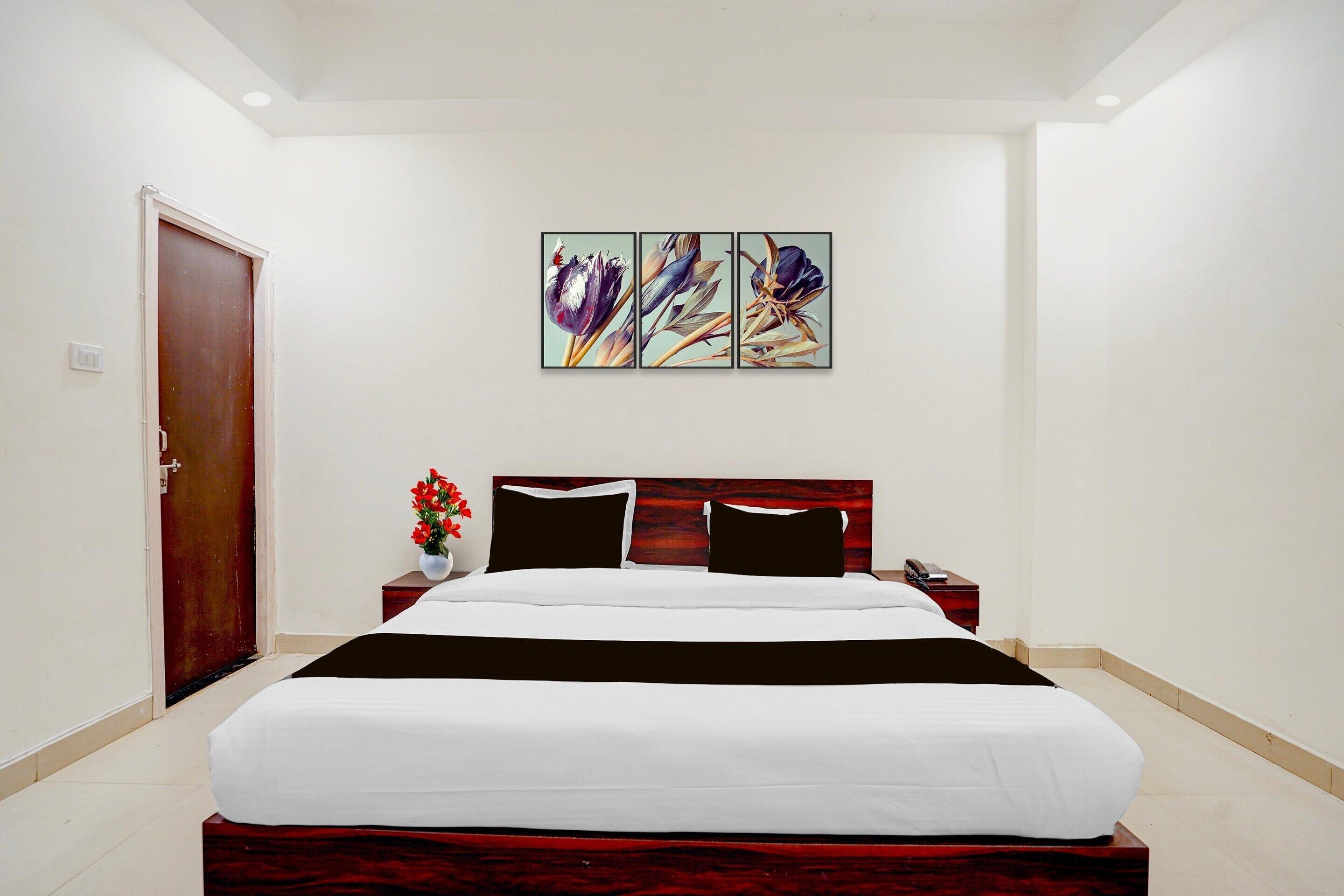 Une chambre d’hôtel avec un lit, une table de chevet, un téléphone et un tableau accroché au mur.
