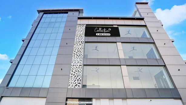 A modern building with a glass facade, a sign reading 'Collection,' and a decorative panel.