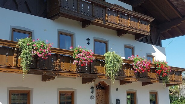 Ein traditionelles Chalet mit hölzernen Balkonen, Blumenkästen und Holzbanken.