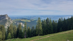 Eine Berglandschaft mit freiem Blick auf ein Tal und ein Gewässer in der Ferne.