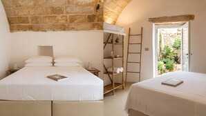 A bedroom with a stone wall, a bed with white bedding, a wooden ladder, and a door leading to a garden. - Villa 'Resort I Trulli Torre Suda' with Private Pool, Wi-Fi and Air Conditioning (Torre Suda)