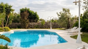A swimming pool with lounge chairs and a stone wall in the background. - Villa 'Resort I Trulli Torre Suda' with Private Pool, Wi-Fi and Air Conditioning (Torre Suda)