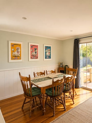 Een eetkamer met een houten tafel en stoelen, lijstwerken aan de muur en uitzicht door een raam.