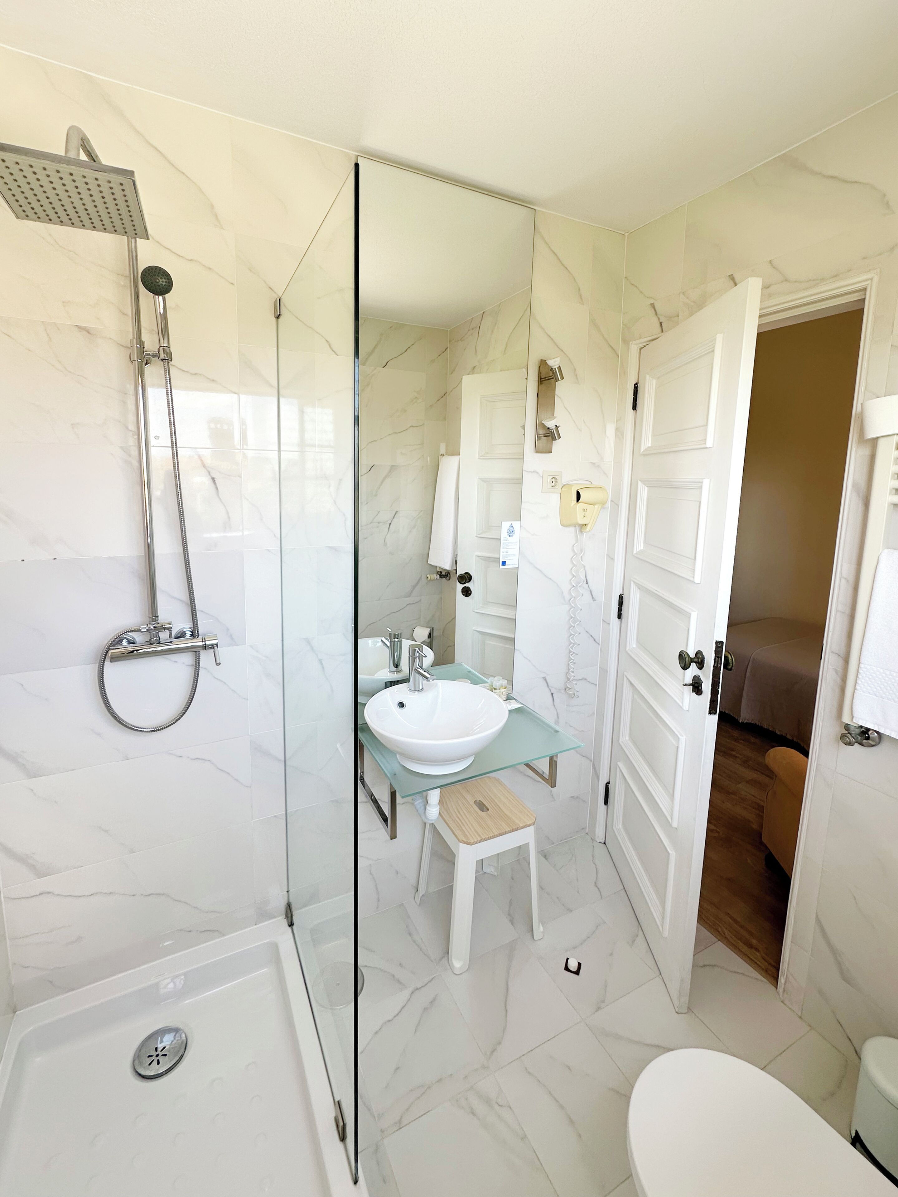 A modern bathroom with a glass-enclosed shower, a white sink, and a toilet.