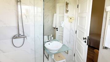 A modern bathroom with a glass-enclosed shower, a white sink, and a toilet.