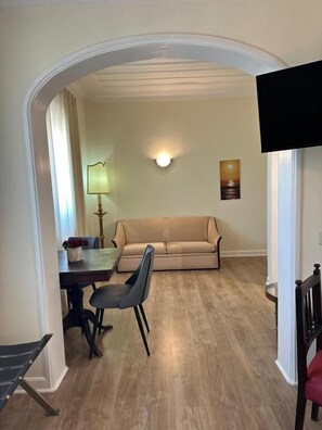 A dining area with a table and chairs, a sofa, a lamp, and a television. - Hotel João Padeiro (Cacia)