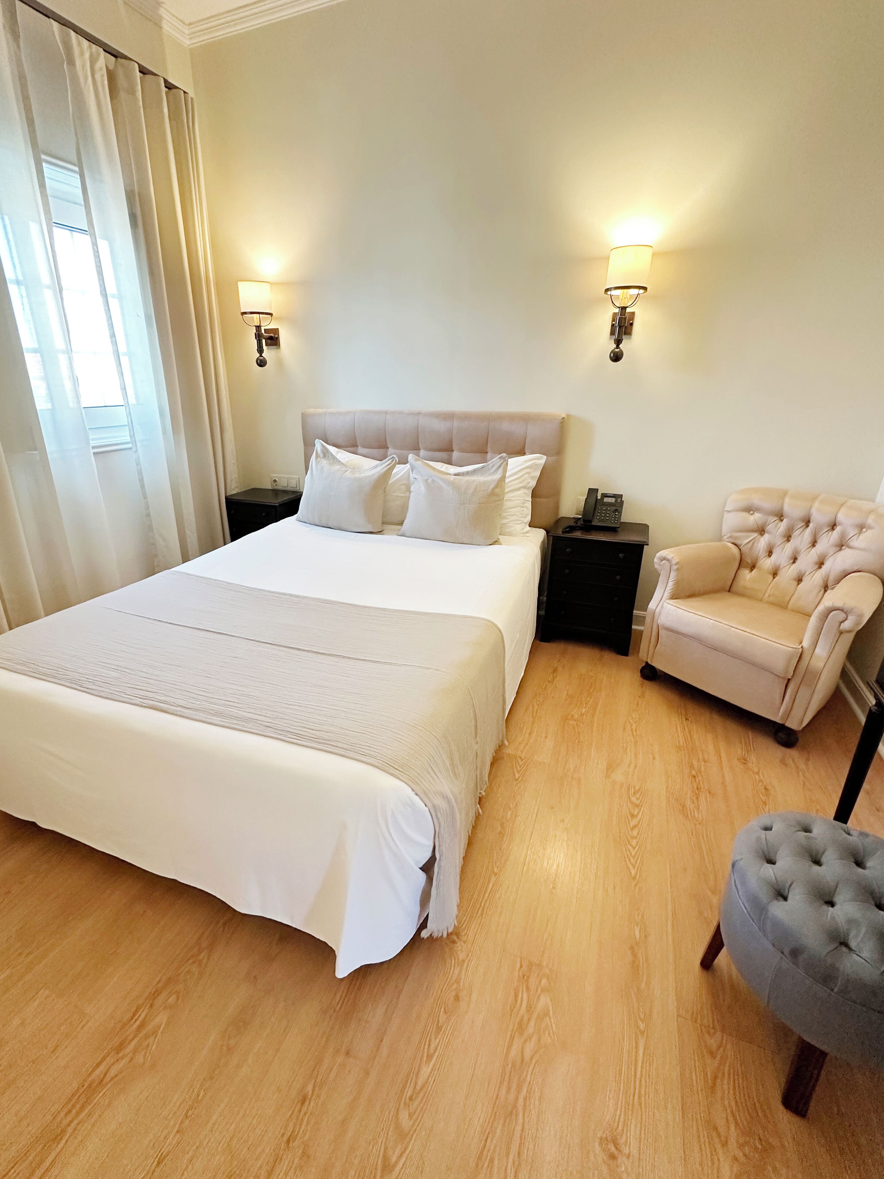 A hotel room with a large bed, two bedside tables, a chair, and a lamp.