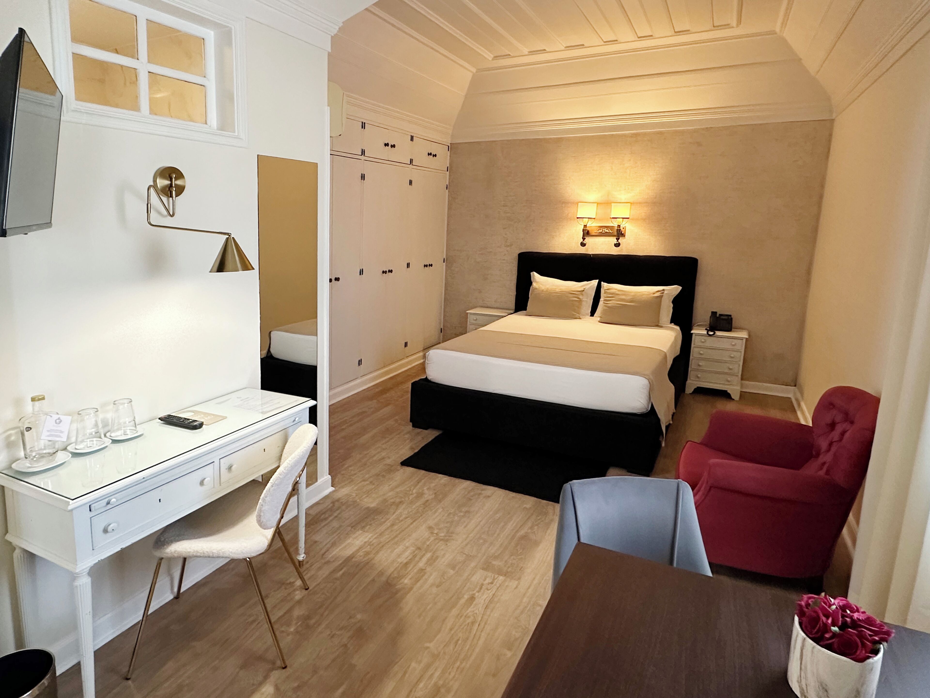 A bedroom with a bed, desk, chair, and a red armchair.