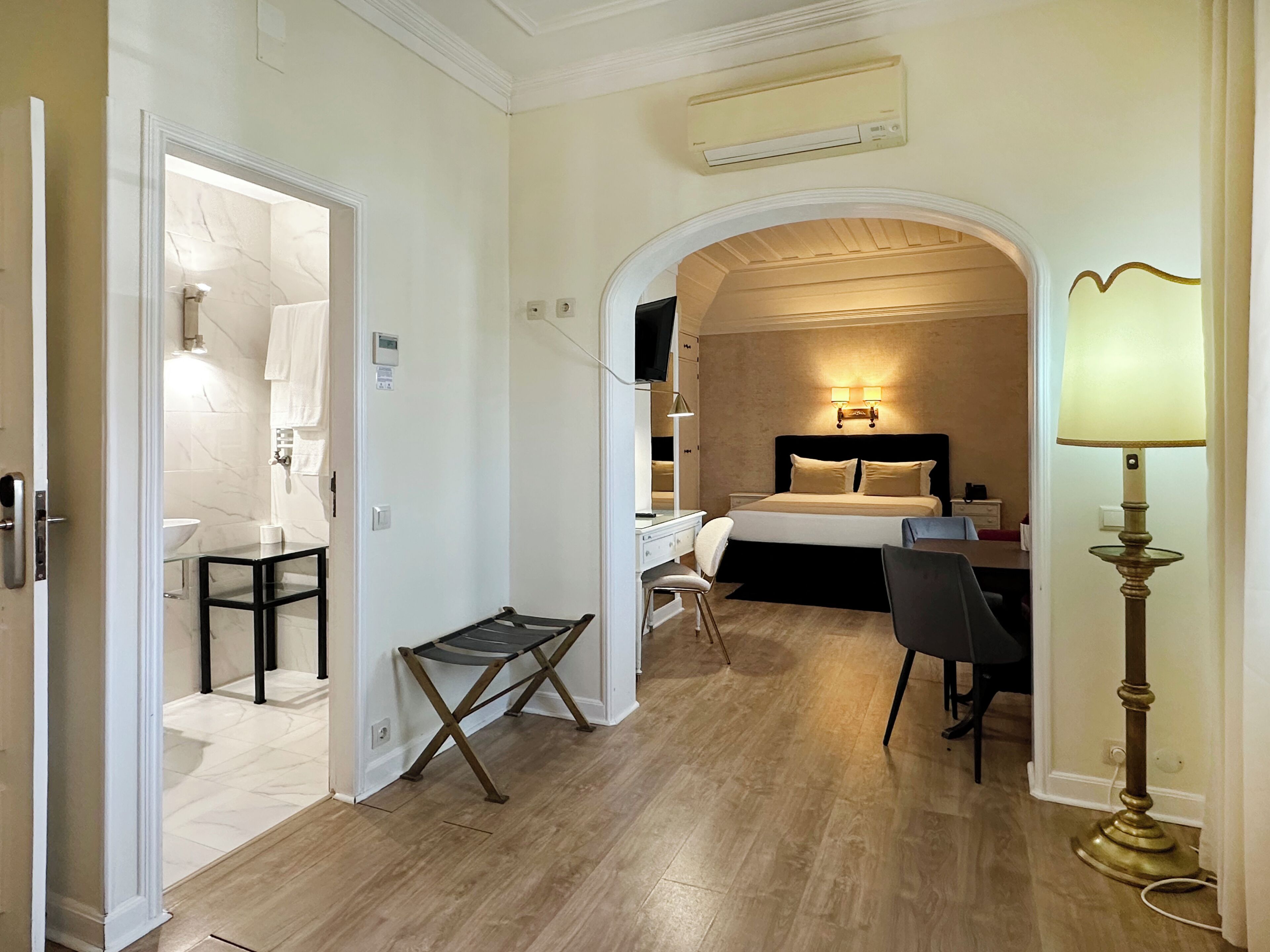 Une chambre d’hôtel avec un lit, un bureau, une chaise et une petite table.