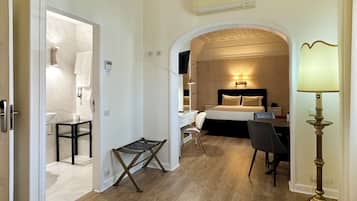 A hotel room with a bed, desk, chair, and a small table.