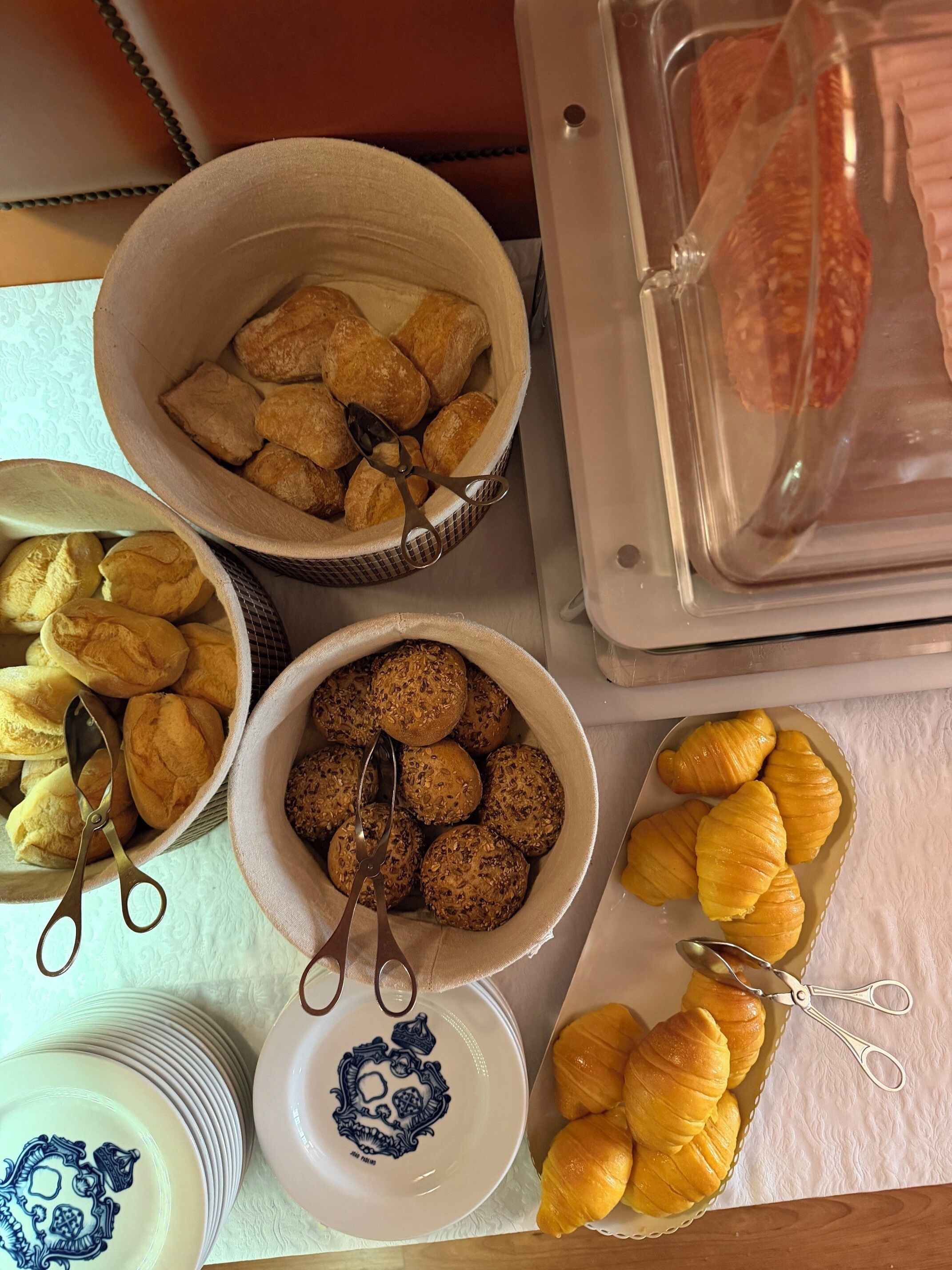 A table with various baked goods, including bread rolls and croissants, with a pair of scissors on each.