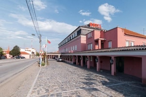 Un edificio rosa con un letrero que dice 'HOTEL' y una calle empedrada al frente.
