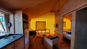 Un intérieur compact en bois comprenant un coin cuisine, un canapé, une petite table et un lit superposé.