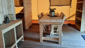 Une table de salle à manger en bois, avec des chaises, une plante en pot et un petit meuble.